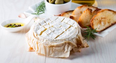 Pişmiş camembert peyniri. Taze Brie peyniri ve bir dilim fındık, tatlım, biberiye ile ahşap bir gemide, baget ekmek ızgara tost ve yaprakları. Peynir Brie türü. İtalyan, Fransız peynir.