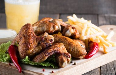 Yakın çekim fotoğraf Barbekü tavuk kanatlı patates ve bira. Barbekü soslar, ketçap, mayonez etli. Hızlı ve abur cubur kavramı. 