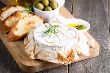 Pişmiş camembert peyniri. Taze Brie peyniri ve bir dilim fındık, tatlım, biberiye ile ahşap bir gemide, baget ekmek ızgara tost ve yaprakları. Peynir Brie türü. İtalyan, Fransız peynir.