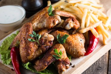 Yakın çekim fotoğraf Barbekü tavuk kanatlı patates ve bira. Barbekü soslar, ketçap, mayonez etli. Hızlı ve abur cubur kavramı. 