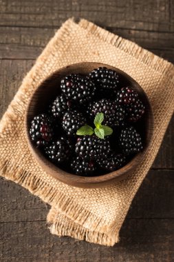 Ahşap arka plan üzerinde ahşap bir kase taze organik olgun böğürtlen. Sağlıklı rustik gıda konsepti.