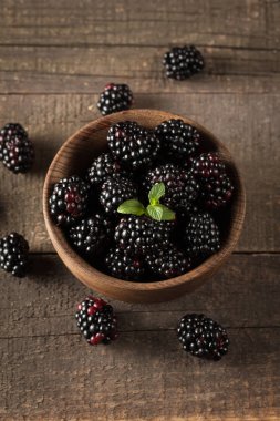 Ahşap arka plan üzerinde ahşap bir kase taze organik olgun böğürtlen. Sağlıklı rustik gıda konsepti.