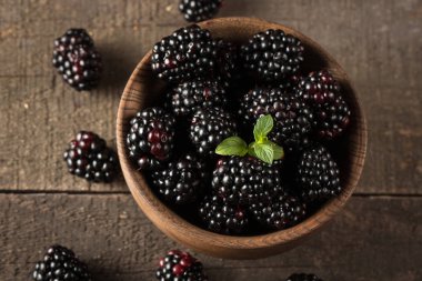 Ahşap arka plan üzerinde ahşap bir kase taze organik olgun böğürtlen. Sağlıklı rustik gıda konsepti.