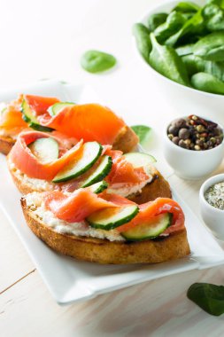 Somon, salatalık ve krem peynir bruschetta. İtalyan tapas antipasti sebzeler, otlar ve ızgara ciabatta ve baget ekmek üzerine. Sandviç.