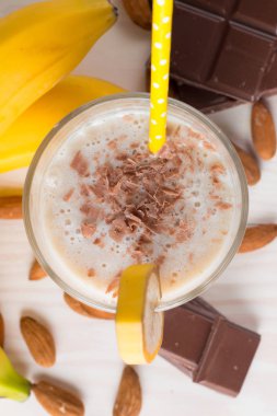 Taze yapılmış çikolata muz Smoothie ahşap bir masa üzerinde. Seçici odak. Bademli muzlu süt. Protein diyeti. Sağlıklı yiyecek ve içecek konsepti.