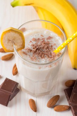 Taze yapılmış çikolata muz Smoothie ahşap bir masa üzerinde. Seçici odak. Bademli muzlu süt. Protein diyeti. Sağlıklı yiyecek ve içecek konsepti.