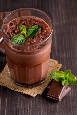 Çikolata, kahve, süt, muz sallamak ahşap arka plan üzerinde. Nane ile güler yüzlü. Milkshake. Protein diyeti. Sağlıklı yiyecek ve içecek konsepti.