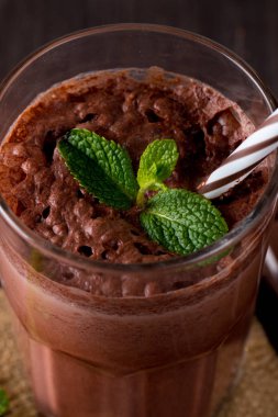 Çikolata, kahve, süt, muz sallamak ahşap arka plan üzerinde. Nane ile güler yüzlü. Milkshake. Protein diyeti. Sağlıklı yiyecek ve içecek konsepti.