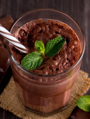 Çikolata, kahve, süt, muz sallamak ahşap arka plan üzerinde. Nane ile güler yüzlü. Milkshake. Protein diyeti. Sağlıklı yiyecek ve içecek konsepti.