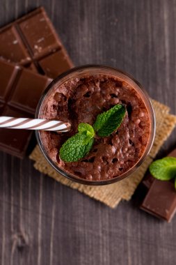 Çikolata, kahve, süt, muz sallamak ahşap arka plan üzerinde. Nane ile güler yüzlü. Milkshake. Protein diyeti. Sağlıklı yiyecek ve içecek konsepti.