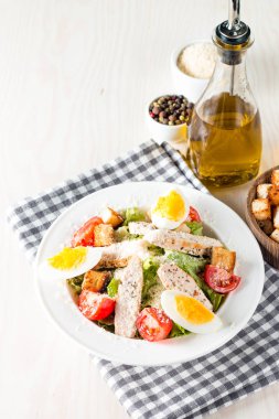 Taze salata domates, ruccola, tavuk göğsü, yumurta, roka, kraker ve baharat yapılmış. Ahşap arka plan üzerinde beyaz, şeffaf bir kasede Sezar salatası
