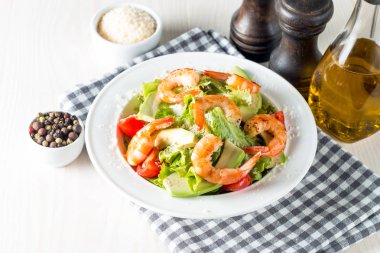 Domates, ruccola, avokado, karides, tavuk göğsü, arugula, kraker ve baharatyapılmış taze karides salatası. Ahşap arka plan üzerinde beyaz, şeffaf bir kapta Sezar salatası