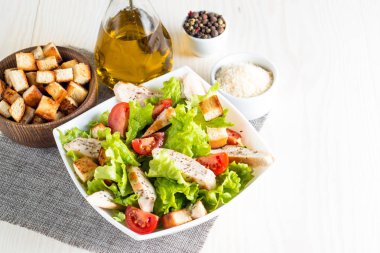 Taze salata domates, ruccola, tavuk göğsü, yumurta, roka, kraker ve baharat yapılmış. Ahşap arka plan üzerinde beyaz, şeffaf bir kasede Sezar salatası