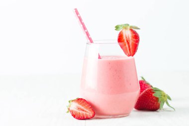 Ahşap arka planda bir bardak taze çilekli smoothie. Yaz içeceği, milkshake, meyve suyu ve ferahlatıcı organik konsept..