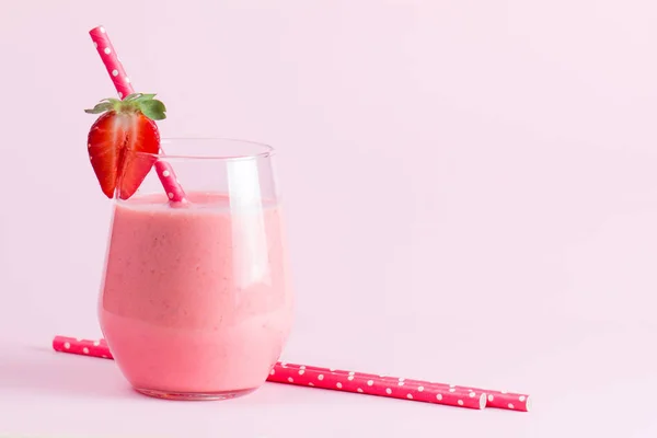 A glass of fresh strawberry smoothie on a wooden background. Summer drink shake, milkshake, juice and refreshment organic concept.