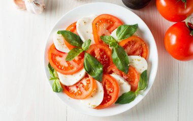 Caprese salatası olgun domates, fesleğen, buffalo mozzarella peyniri ile yakın çekim fotoğraf. İtalyan ve Akdeniz gıda kavramı. Taze ve sağlıklı organik yemek. Starter ve antipasti. 