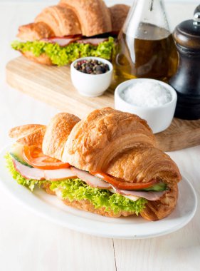 Taze kruvasan veya sandviç salata, jambon, jamon, jambon, salam, peynir, tavuk, domates ahşap arka plan ile. Sabah kahvaltı kavramı. Sağlıklı ve fast food.
