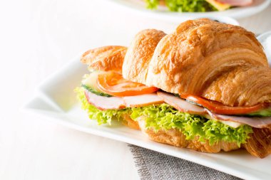 Taze kruvasan veya sandviç salata, jambon, jamon, jambon, salam, peynir, tavuk, domates ahşap arka plan ile. Sabah kahvaltı kavramı. Sağlıklı ve fast food.