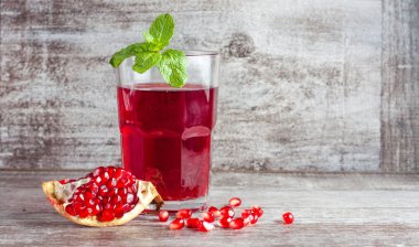 Bir bardak nar suyu ve ahşap masada taze nar meyveleri. Vitamin ve mineraller. Sağlıklı içki konsepti.