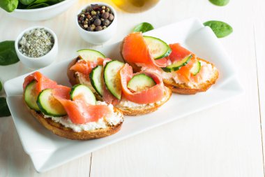 Somon, salatalık ve krem peynir bruschetta. İtalyan tapas antipasti sebzeler, otlar ve ızgara ciabatta ve baget ekmek üzerine. Sandviç.