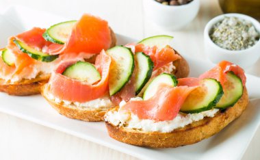 Somon, salatalık ve krem peynir bruschetta. İtalyan tapas antipasti sebzeler, otlar ve ızgara ciabatta ve baget ekmek üzerine. Sandviç.