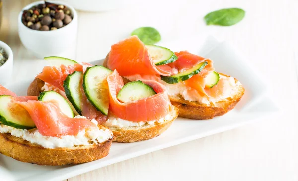 Somon, salatalık ve krem peynir bruschetta. İtalyan tapas antipasti sebzeler, otlar ve ızgara ciabatta ve baget ekmek üzerine. Sandviç.