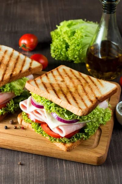 俱乐部三明治的特写镜头 在木制背景下的新鲜黑麦面包上加入肉 意大利香肠 西红柿 洋葱和芥末 橄榄背景 — 图库照片