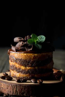 Çikolatalı kek siyah slatter kurulu ile nane, kahve çekirdekleri koyu arka plan, closeup fotoğraf üzerinde. Taze, lezzetli tatlı gıda kavramı. 