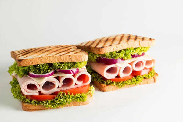 Close-up photo of a club sandwich. Sandwich with meat, prosciutto, salami, salad, vegetables, lettuce, tomato, onion and mustard on a fresh sliced rye bread on wooden background. Olives background.