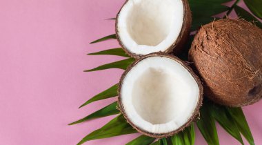 Pembe arka planda kremalı ve yeşil yapraklı olgun hindistan cevizi.. 