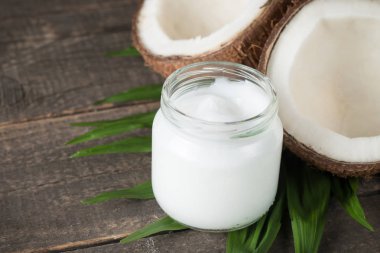 Ahşap arka planda yeşil yapraklı, yarım kesilmiş hindistan cevizi.. 