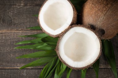 Ahşap arka planda yeşil yapraklı, yarım kesilmiş hindistan cevizi.. 