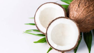 Beyaz arka planda yeşil yapraklı, yarım kesilmiş hindistan cevizi. Ayrı bir kavram. 