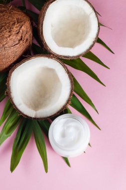 Pembe arka planda kremalı ve yeşil yapraklı olgun hindistan cevizi.. 