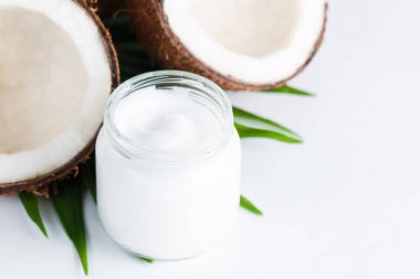 Olgun, yarım kesilmiş hindistan cevizi ve yeşil yapraklı krema beyaz, izole bir zemin. Sağlık ve tıbbi konsept. Cilt bakımı. 