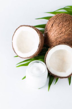 Olgun, yarım kesilmiş hindistan cevizi ve yeşil yapraklı krema beyaz, izole bir zemin. Sağlık ve tıbbi konsept. Cilt bakımı. 