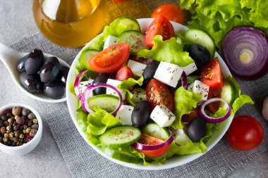 Kiraz domates, ruccola, roka, beyaz peynir, zeytin, salatalık, soğan ve baharat taze Yunan salatası yaptı. Sezar salatası ahşap arka plan üzerinde beyaz bir kase. Sağlıklı organik beslenme gıda kavramı.