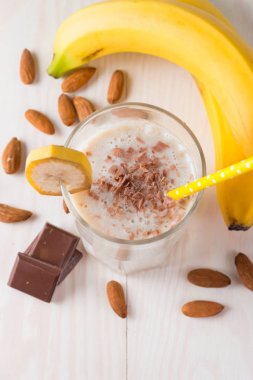 Taze yapılmış çikolata muz Smoothie ahşap bir masa üzerinde. Seçici odak. Bademli muzlu süt. Protein diyeti. Sağlıklı yiyecek ve içecek konsepti.