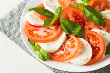 Caprese salatası olgun domates, fesleğen, buffalo mozzarella peyniri ile yakın çekim fotoğraf. İtalyan ve Akdeniz gıda kavramı. Taze ve sağlıklı organik yemek. Starter ve antipasti. 