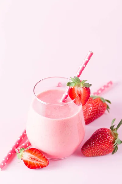 A glass of fresh strawberry smoothie on a wooden background. Summer drink shake, milkshake, juice and refreshment organic concept.