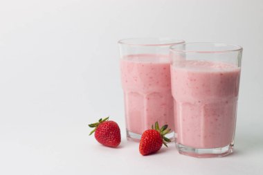 Beyaz arka planda bir bardak taze çilekli smoothie. Yaz içeceği, milkshake ve ferahlatıcı organik konsept..