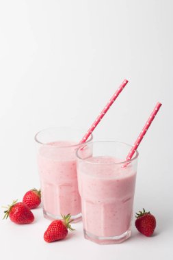 Beyaz arka planda bir bardak taze çilekli smoothie. Yaz içeceği, milkshake ve ferahlatıcı organik konsept..