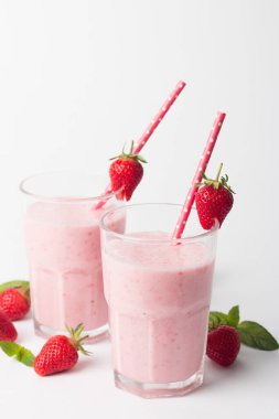 Beyaz arka planda bir bardak taze çilekli smoothie. Yaz içeceği, milkshake ve ferahlatıcı organik konsept..