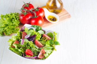 Çeri domates, roka, roka, feta, zeytin, salatalık, soğan ve baharattan yapılmış taze ve sağlıklı sebze salatası. Yunan, Sezar salatası beyaz bir kâse içinde ahşap arka planda. Sağlıklı organik diyet gıda konsepti.