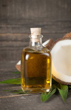 Ahşap arka planda yeşil yapraklı, yarım kesilmiş hindistan cevizi.. 