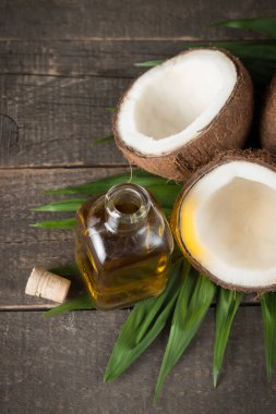 Ahşap arka planda yeşil yapraklı, yarım kesilmiş hindistan cevizi.. 