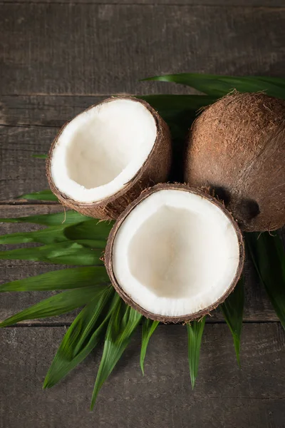 Rijp Half Gesneden Kokosnoot Met Groene Bladeren Een Houten Ondergrond — Stockfoto