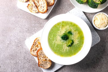 Sıcak ve rahatlatıcı kremalı brokoli çorbası bir kasede servis edilir, parmesan peyniri ve kızarmış ekmekle süslenir..