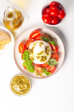 Çeri domatesli Burrata peynirli Caprese salatası, zeytin yağı, pesto ve baharat. Taze gıda konsepti. 