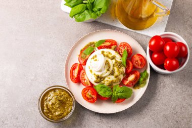Çeri domatesli Burrata peynirli Caprese salatası, zeytin yağı, pesto ve baharat. Taze gıda konsepti. 